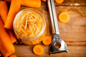 Canned carrots in a glass jar on the table. photo