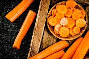 Whole and sliced carrots on a wooden tray. photo