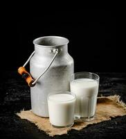 rústico Leche en un lata y un vaso en el mesa. foto