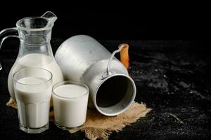 Rustic milk in a can and a glass on the table. photo
