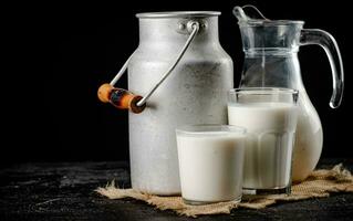 Rustic milk in a can and a glass on the table. photo
