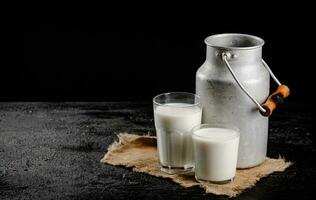 Rustic milk in a can and a glass on the table. photo