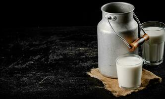 rústico Leche en un lata y un vaso en el mesa. foto