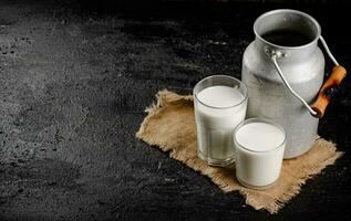 rústico Leche en un lata y un vaso en el mesa. foto