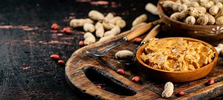 Peanut butter and inshell peanuts on a cutting board. photo