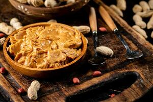 Peanut butter and inshell peanuts on a cutting board. photo