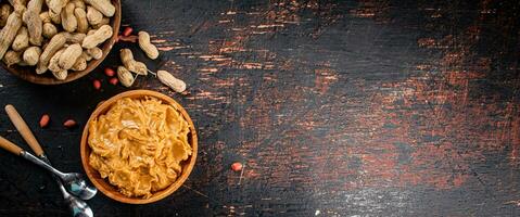 Peanut butter and inshell peanuts in wooden plates. photo