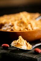 Peanut butter in a spoon on a cutting board. photo