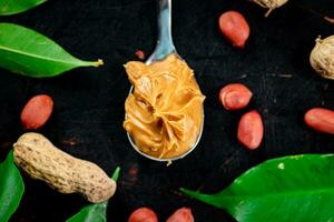 A spoonful of peanut butter on a table with leaves. photo