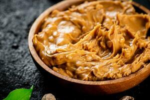 Peanut butter in a wooden plate on the table. photo