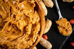 Peanut butter on a stone board with peanuts in the shell. photo