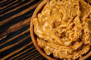 A plate of peanut butter on a wooden background. photo