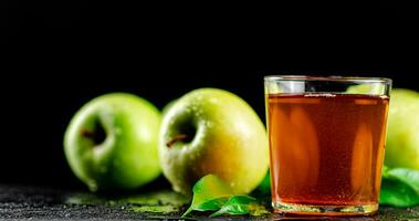 A glass of green apple juice with leaves on the table. photo