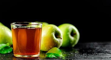 A glass of green apple juice with leaves on the table. photo