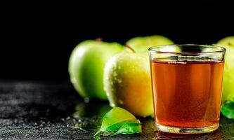 un vaso de verde manzana jugo con hojas en el mesa. foto