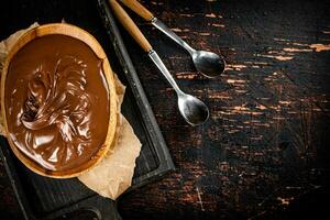 Hazelnut butter in a plate on a cutting board with paper. photo