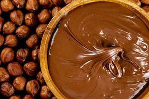 Hazelnut butter on a wooden plate with peeled hazelnuts. photo