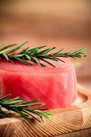 A steak of raw tuna on a cutting board with a sprig of rosemary. photo