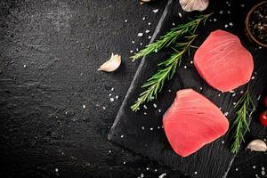 Raw tuna on a stone board with rosemary and garlic. photo