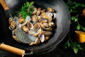 Vongole in a saucepan with lemon slices and parsley. photo