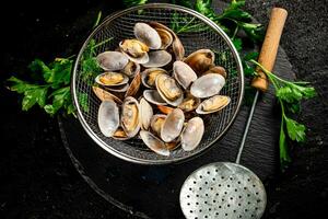 Fresh vongole in a colander on a stone board with parsley. photo