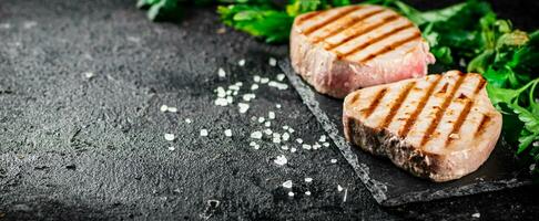 Grilled tuna on a stone board with parsley and salt. photo