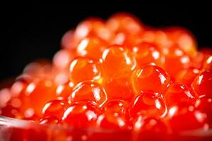 Grains of red caviar on a black background. photo