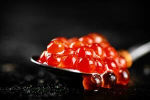 Red caviar in a spoon on the table. photo