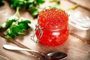 Red caviar in a glass jar with parsley. photo