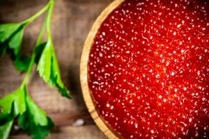 Red caviar in a plate on the table with parsley. photo