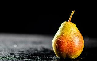 One pear with drops of water on the table. photo