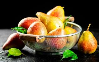 Fresh pears with leaves in a colander. photo