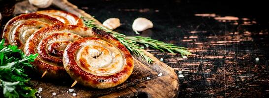 Grilled sausages on a cutting board with parsley and rosemary. photo