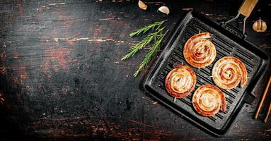 Grilled sausages in a frying pan with a sprig of rosemary. photo