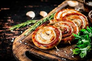 Grilled sausages on a cutting board with parsley and rosemary. photo