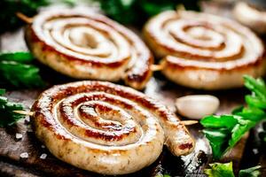 Grilled sausages with garlic and parsley on a wooden background. photo