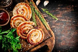 Grilled sausages on a cutting board with tomato sauce, garlic and herbs. photo