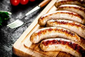 Aromatic grilled sausages on a cutting board. photo