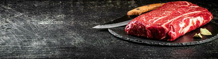 Raw beef on a stone board with a knife. photo