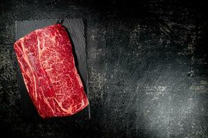 A piece of raw beef on a stone board. photo