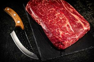 Raw beef on a stone board with a knife. photo