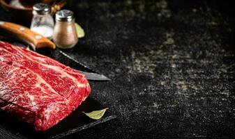 Raw beef on a stone board with spices. photo