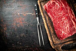 Raw beef on a cutting board with a fork. photo