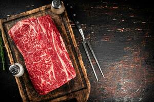 Raw beef on a cutting board with a fork. photo