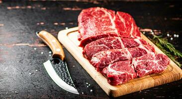 Raw beef on a wooden cutting board with rosemary. photo