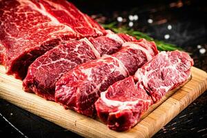 Raw beef on a wooden cutting board with rosemary. photo