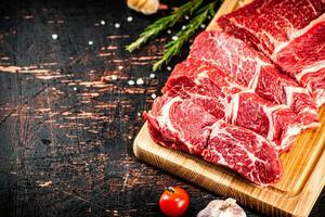 Raw beef on a wooden cutting board with rosemary. photo