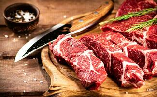 Raw beef on a cutting board with rosemary and spices. photo