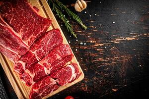 Raw beef on a wooden cutting board with rosemary. photo