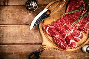 Raw beef on a cutting board with rosemary and spices. photo